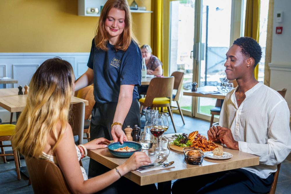 Serveuse apportant un œuf en meurette à un couple attablé au Bistrot de l'O