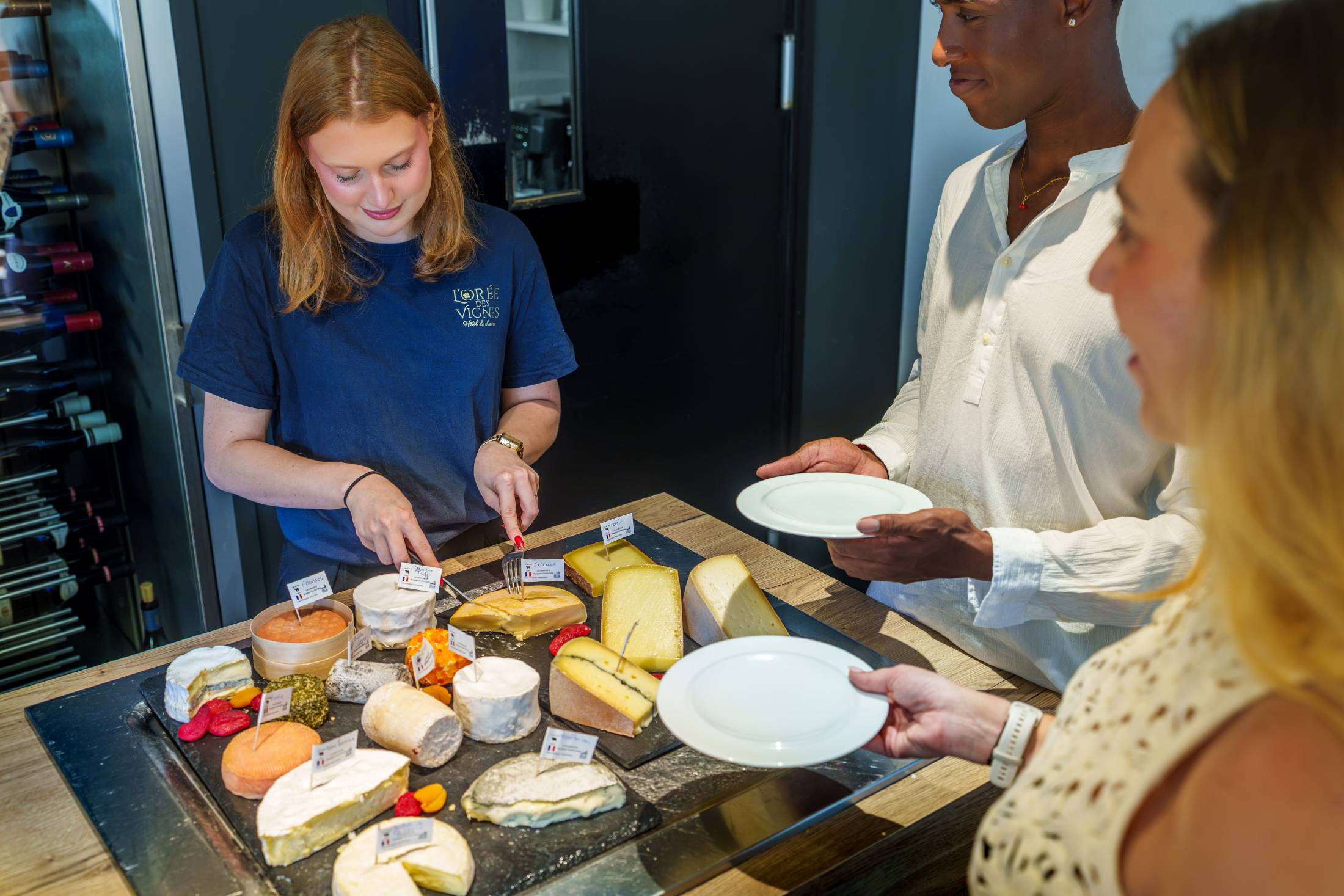 Serveuse proposant une dégustation de fromages régionaux à des clients de l'hôtel L'Orée des Vignes