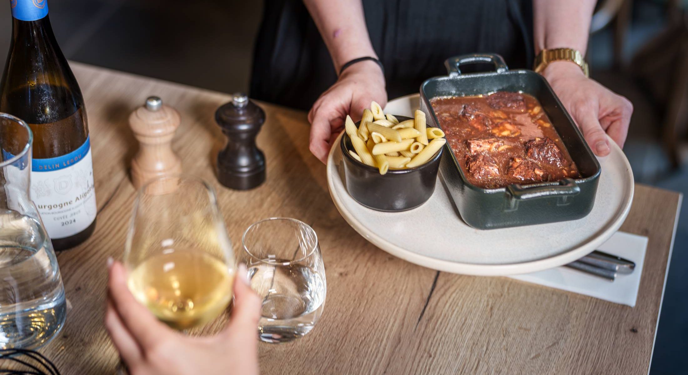 Vue rapprochée du service d'un plat de viande mijotée et de pâtes au restaurant Bistrot de l'O